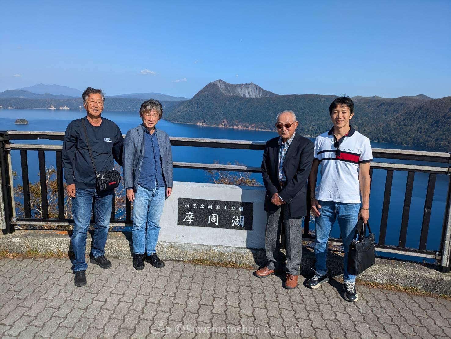 摩周湖を背景にした澤本商事とお客様の記念写真